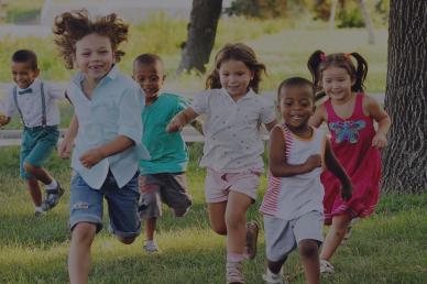 A group of preschoolers running on the grass