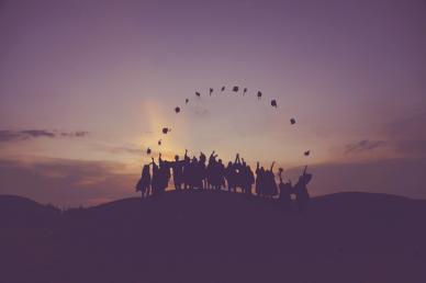 Higher education students throwing academic caps