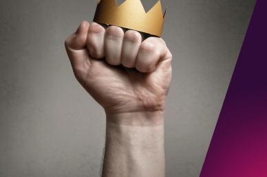Hand gripping a gold paper crown against a textured background