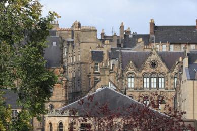 View of historic stone buildings with slate roofs and ornate architectural details by Viola Kovács on Unsplash