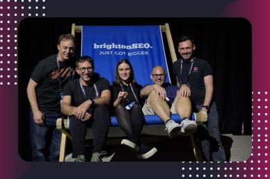 Five brightonSEO 2026 attendees smiling while sitting together on a giant blue beach deckchair at the event