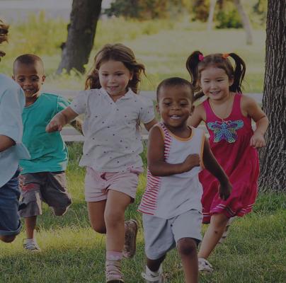 A group of preschoolers running on the grass