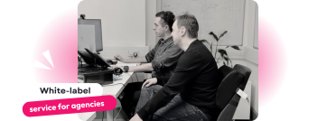 Two professionals collaborating at a desk, seated in front of dual monitors in a modern office setting White-Label Service for Agencies