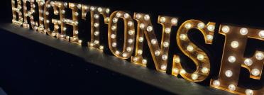 Large glowing marquee letters spelling out brightonSEO against a dark background at the 2026 conference.